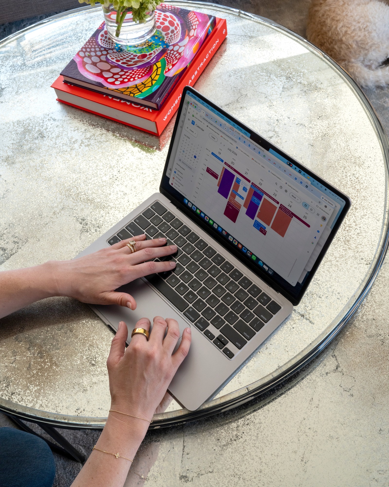 Hands at a laptop on a coffee table, the family calendar open in morning light